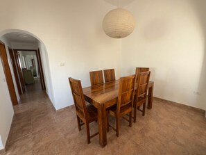 A dining area with a wooden table and chairs, a hanging light fixture, and a hallway leading to another room. - Villa Ann Lanzarote (Nazaret)