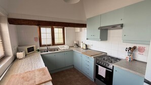 A kitchen with a sink, stove, microwave, and toaster. There are cabinets, a window with blinds, and a countertop. - Villa Ann Lanzarote (Nazaret)