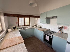 A kitchen with a sink, stove, microwave, and toaster. There are cabinets, a window with blinds, and a countertop. - Villa Ann Lanzarote (Nazaret)