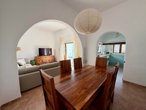 A dining area with a wooden table and chairs, a sofa, and a television in the background. - Villa Ann Lanzarote (Nazaret)