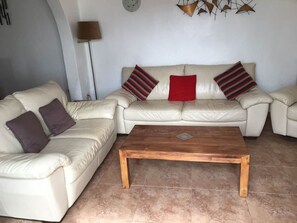 A living room with a beige sofa set, a wooden coffee table, and striped pillows. - Villa Ann Lanzarote (Nazaret)