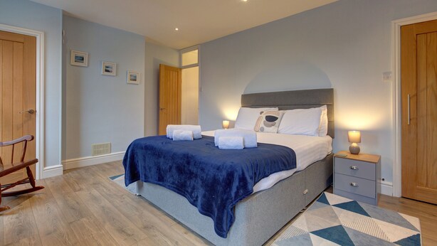A bedroom with a bed, bedside table, and a rocking chair. - Beecroft Cottage - sleeps 4 guests  in 2 bedrooms (Cromer)