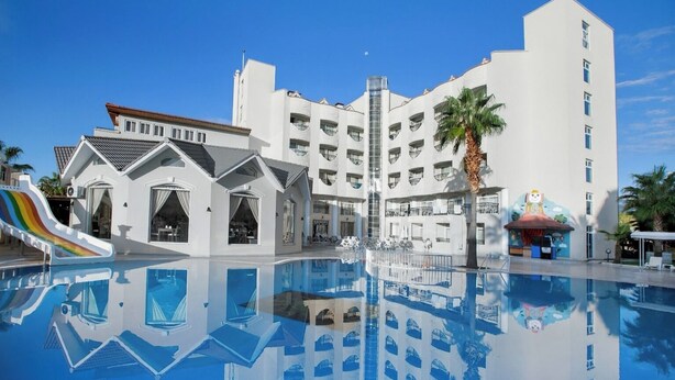 Un hôtel doté d’une piscine, d’un espace de jeux pour enfants et d’un grand bâtiment avec de nombreux balcons.