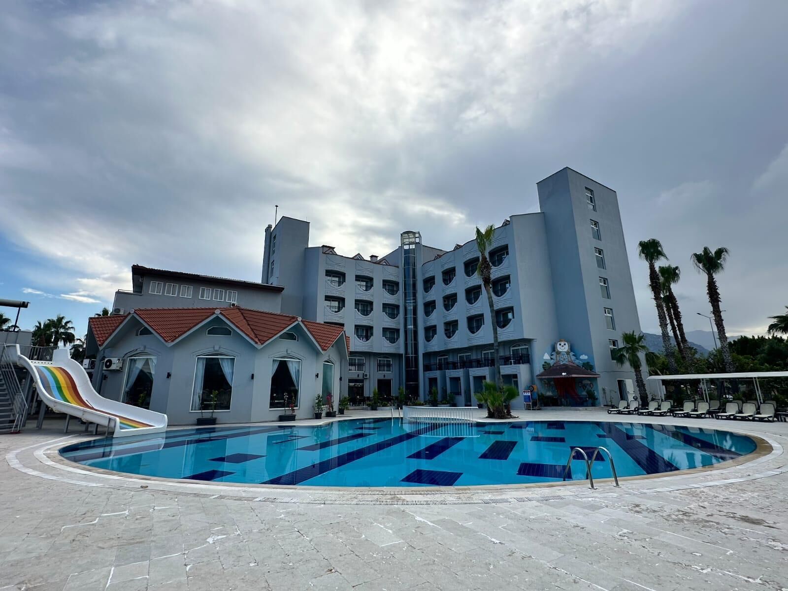 Ein Swimmingpool mit Rutsche, ein mehrstöckiges Gebäude und Palmen.