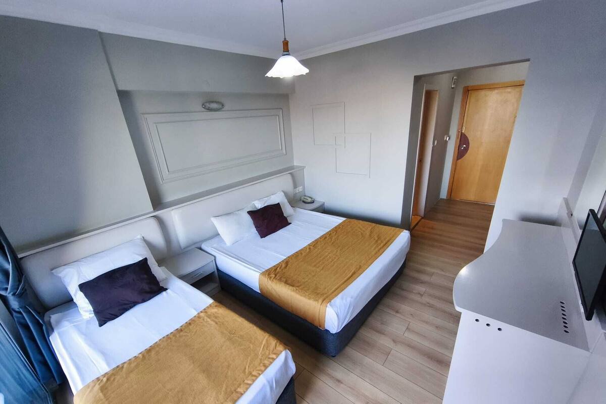 Una habitación de hotel con dos camas, un escritorio, un televisor y una puerta que da a otra habitación.