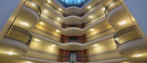 A multi-level atrium with a glass ceiling, multiple balconies, and a central staircase.