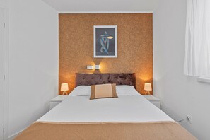 A hotel room with a bed, two bedside lamps, a wall-mounted artwork, and a textured wall. - Superior Apartment Tania 8 (Sveti Filip i Jakov)