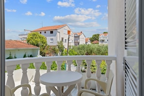 A balcony with a white table and chairs, overlooking a residential area with houses and greenery. - Superior Apartment Tania 8 (Sveti Filip i Jakov)