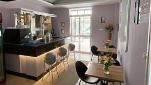 A modern kitchen with a central island, a dining area with a wooden table and chairs, and a large window providing natural light. - Hotel Ornella (Bellaria-Igea Marina)