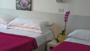 A hotel room with two beds, a nightstand with a lamp, a wall-mounted switch, and a framed picture of an orchid. - Hotel Ornella (Bellaria-Igea Marina)