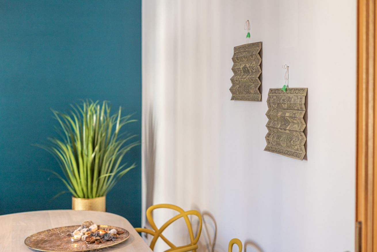 A room with a wooden table, a potted plant, and two wall-mounted decorative items.