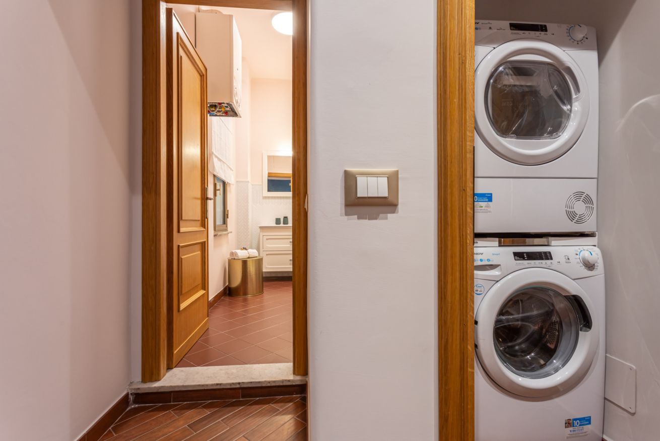 A laundry room with two stacked washing machines and a door leading to a hallway.