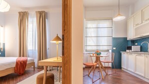 Ein modernes Zimmer mit einem Bett, einem Holztisch und einer Küchenzeile.