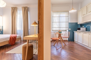 Ein modernes Zimmer mit einem Bett, einem Holztisch und einer Küchenzeile.