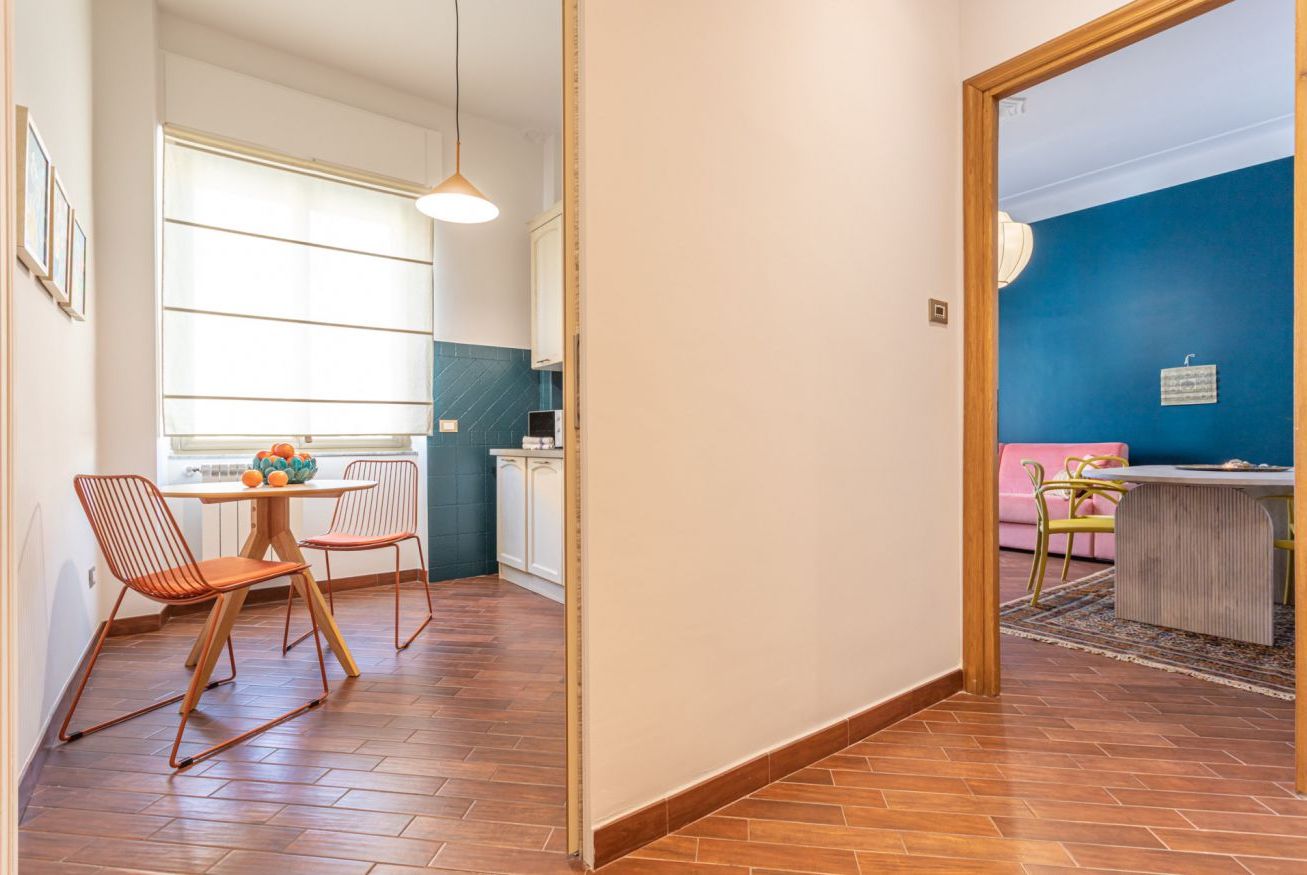 Een moderne keuken met een eethoek, een groot raam en uitzicht op een blauwe muur.