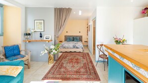 Une pièce comprenant un lit, un canapé, une petite table, une chaise, un tapis et une étagère murale décorative.