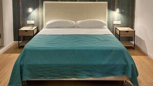A hotel room with a bed, two bedside tables, a nightstand, a wall-mounted light, and a curtain. - suite la pennichella (Agropoli)