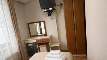 A hotel room with a bed, a desk, a television, a wardrobe, and a mirror.