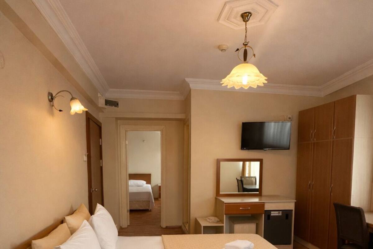 A hotel room with a large bed, a desk, a TV, and a wardrobe.