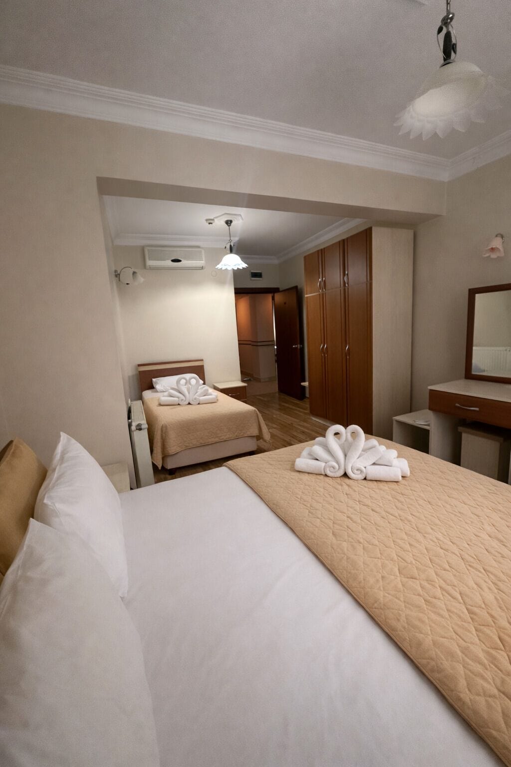 A hotel room with a large bed, a bedside table, a mirror, and a wardrobe.