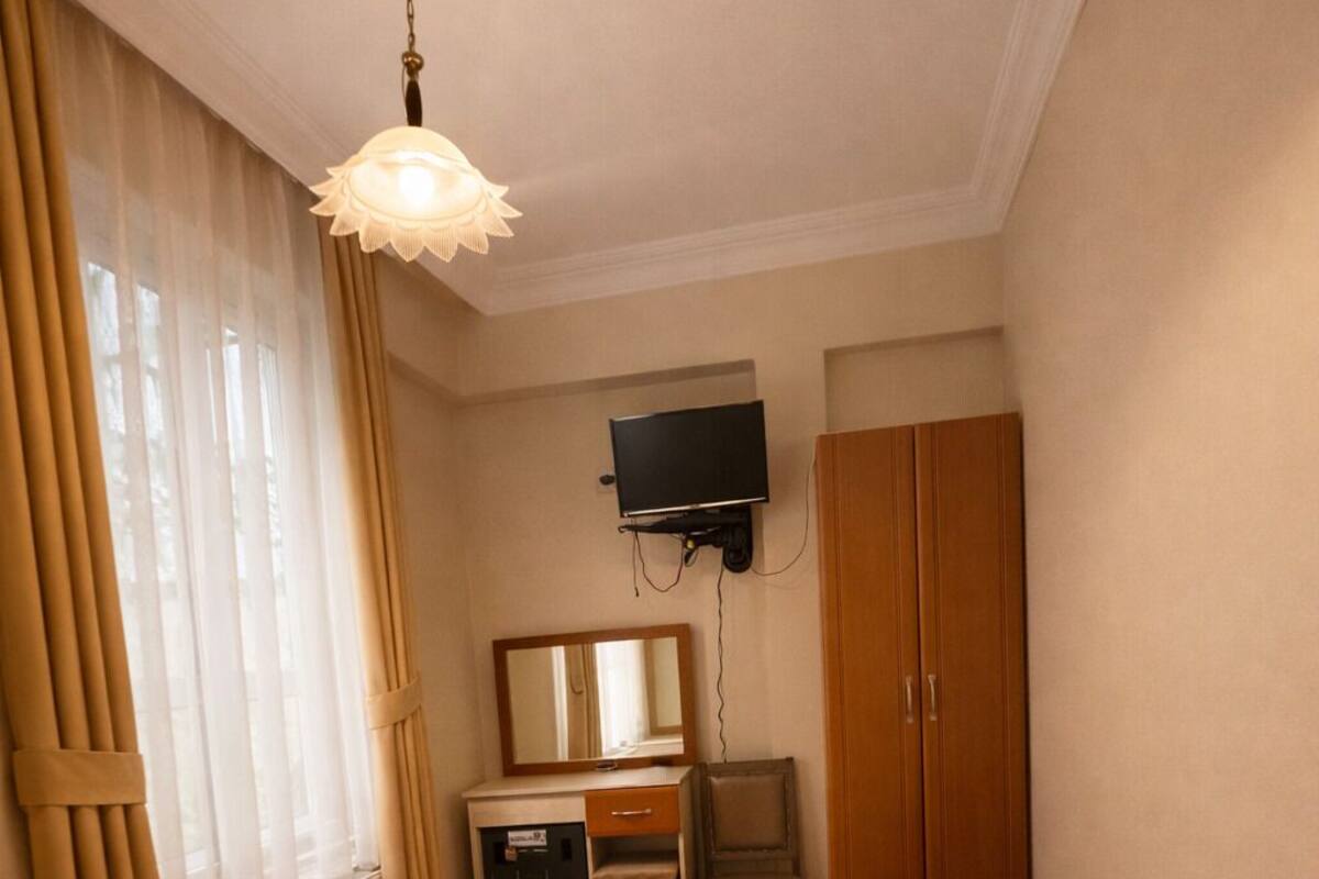 A hotel room with a bed, a desk, a television mounted on the wall, and a wardrobe.