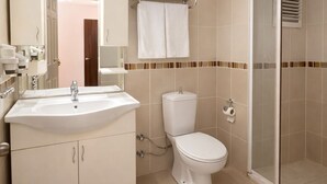 Un baño moderno con lavamanos, inodoro y cabina de ducha de vidrio.