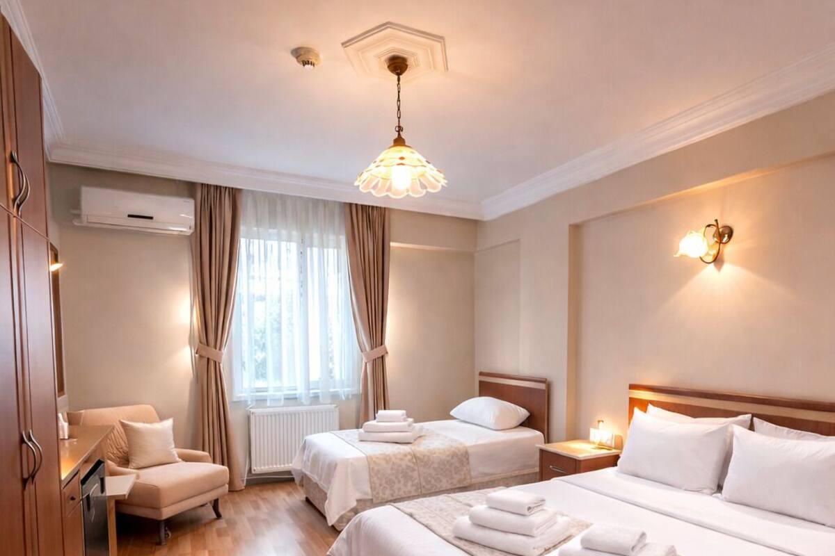 A hotel room with two beds, a sitting area, and a view of the outdoors.