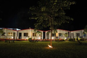 A building with a red roof, multiple windows, and outdoor seating areas.