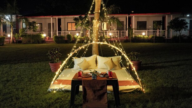 Ein Zelt auf der Wiese mit Tisch und Stühlen, umgeben von Lichterketten.