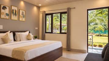 Un dormitorio con una cama grande, una ventana con cortinas y vistas a la vegetación.