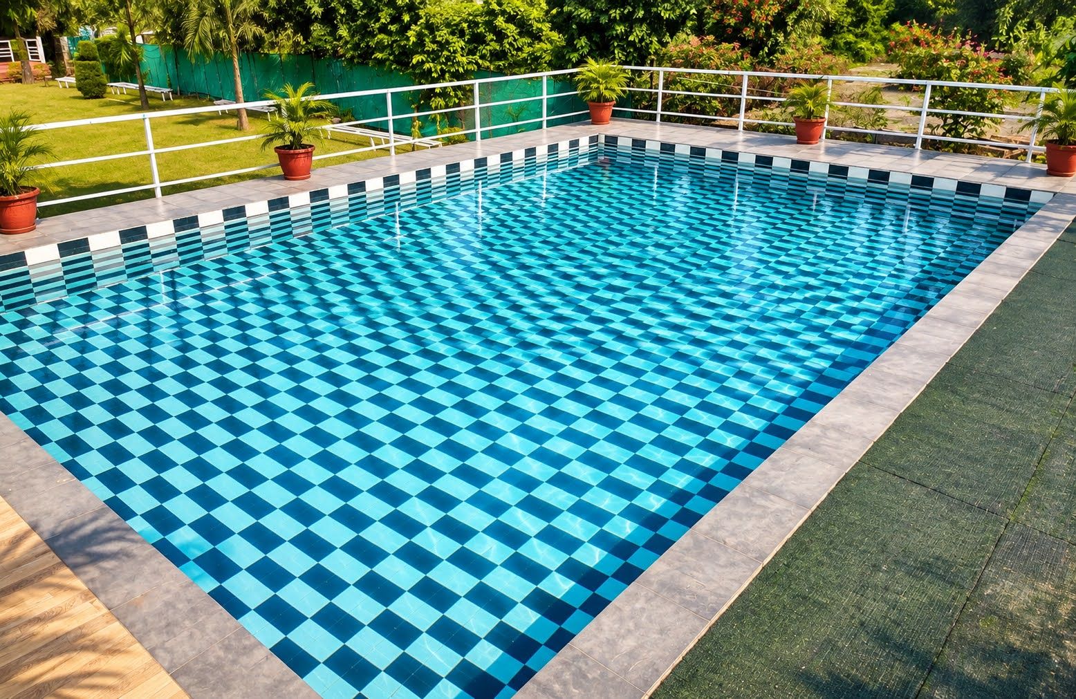 Piscina rectangular con diseño ajedrezado, rodeada por una baranda blanca y macetas con plantas.