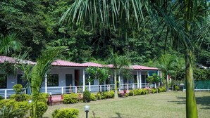 Ein Hotel mit einem rotgedeckten Gebäude, umgeben von üppiger Vegetation und einem gepflegten Rasen.