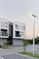 Um hotel moderno com fachada plana, varandas e uma placa com a inscrição "hotelnode".