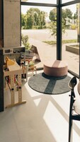 Quarto moderno e bem iluminado, com grandes janelas, um banquinho redondo e um espaço de brincadeiras de madeira com brinquedos e livros.