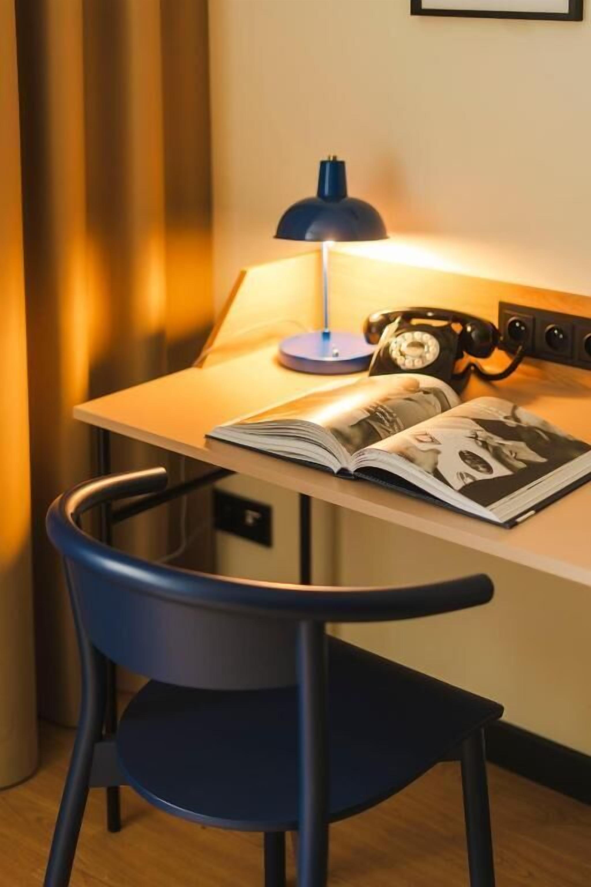 A desk with a lamp, a book, and a rotary phone.