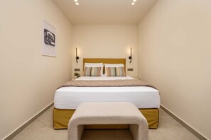 Ein Schlafzimmer mit einem Bett, Nachttischen, einer Wandleuchte und einem gerahmten Bild an der Wand.