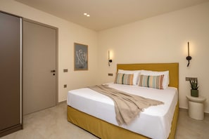 A bedroom with a bed, a door, a wall-mounted light, and a small potted plant.