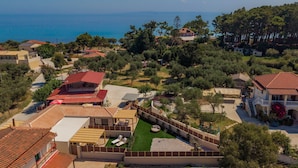 Vista aérea de uma área residencial costeira com casas, com uma vista clara do mar e gramados bem cuidados.