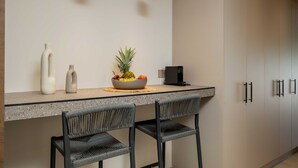 Uma cozinha com bancada de granito, dois banquetes, uma fruteira, um vaso branco e uma máquina de café preta.
