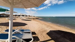 A beach with white umbrellas and lounge chairs. - Arena Beach Resort (Hurghada)