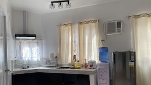 Een kleine keuken met een ingebouwde magnetron, een waterdispenser en een koelkast.