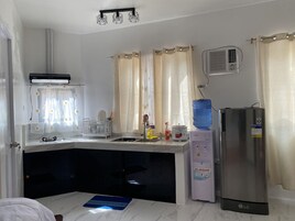 Una cocina compacta con microondas integrado, dispensador de agua y refrigerador.