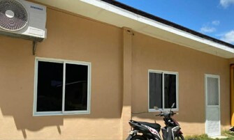 Un edificio con dos ventanas, un equipo de aire acondicionado instalado en la pared y una motocicleta estacionada.