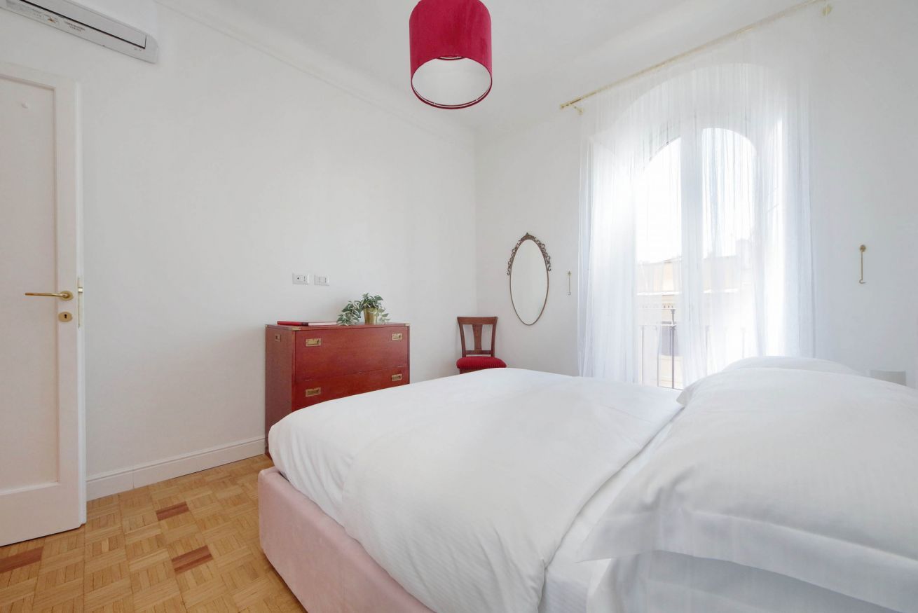 Un dormitorio con una cama grande, un aparador de madera, un espejo y una lámpara roja.