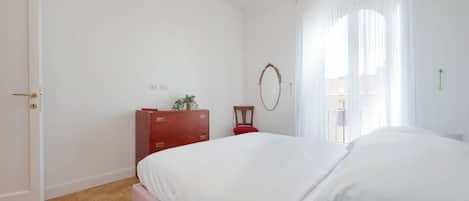 A bedroom with a large bed, a wooden dresser, a mirror, and a red lamp.