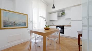 Eine moderne Küche mit weißen Schränken, einem Holztisch mit klaren Stühlen und einem Bild an der Wand.