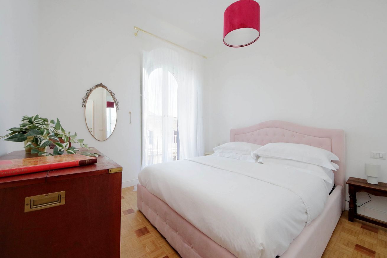 A bedroom with a bed, a dresser, a mirror, and a red lamp.