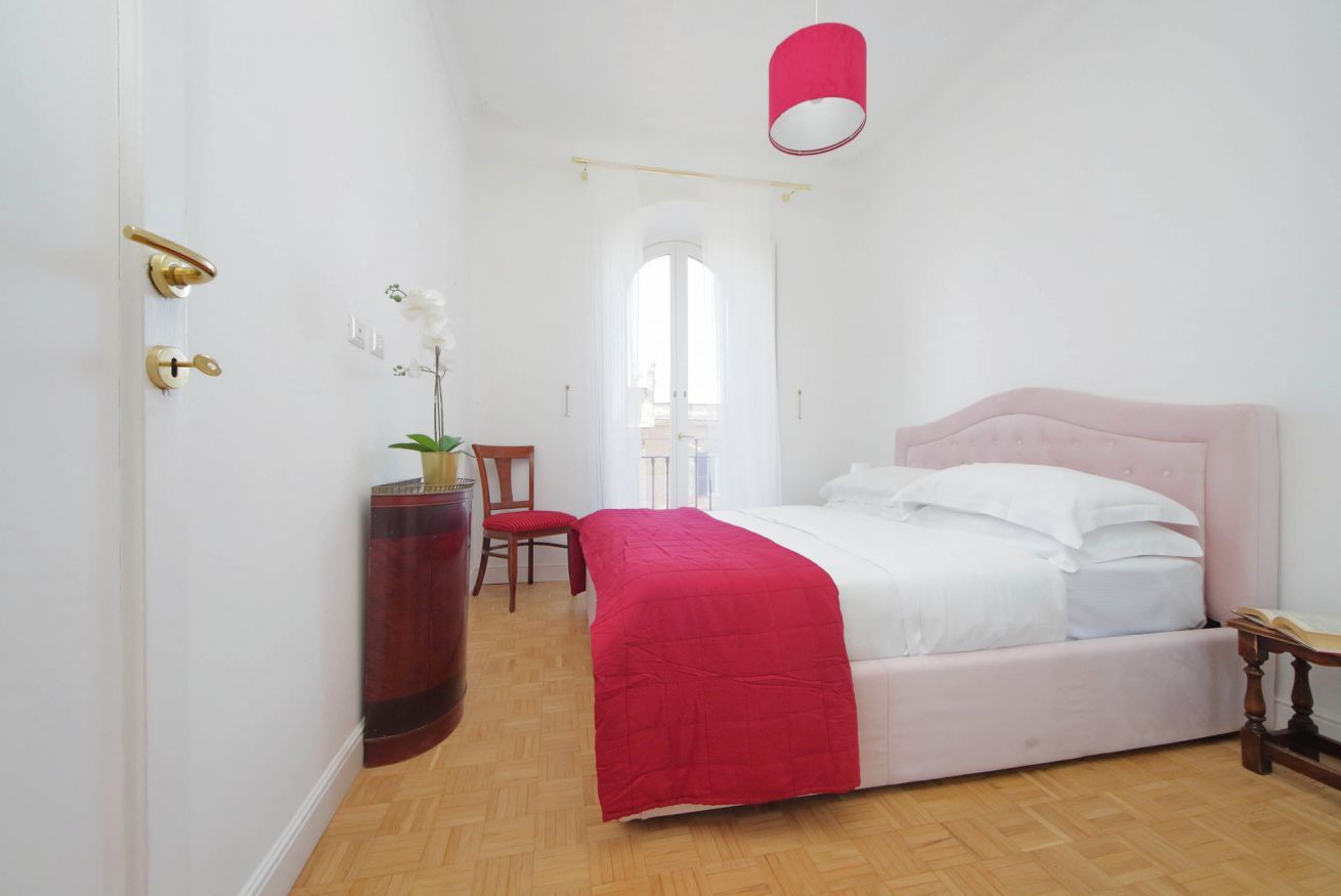 A bedroom with a bed, a chair, a desk, and a window.
