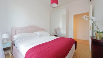 Una camera da letto con un letto, un comodino, uno specchio e una pianta in vaso.