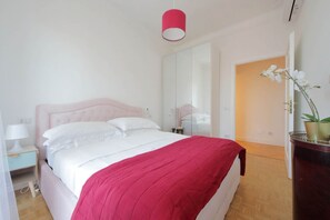 Un dormitorio con cama, mesita de noche, espejo y planta en maceta.